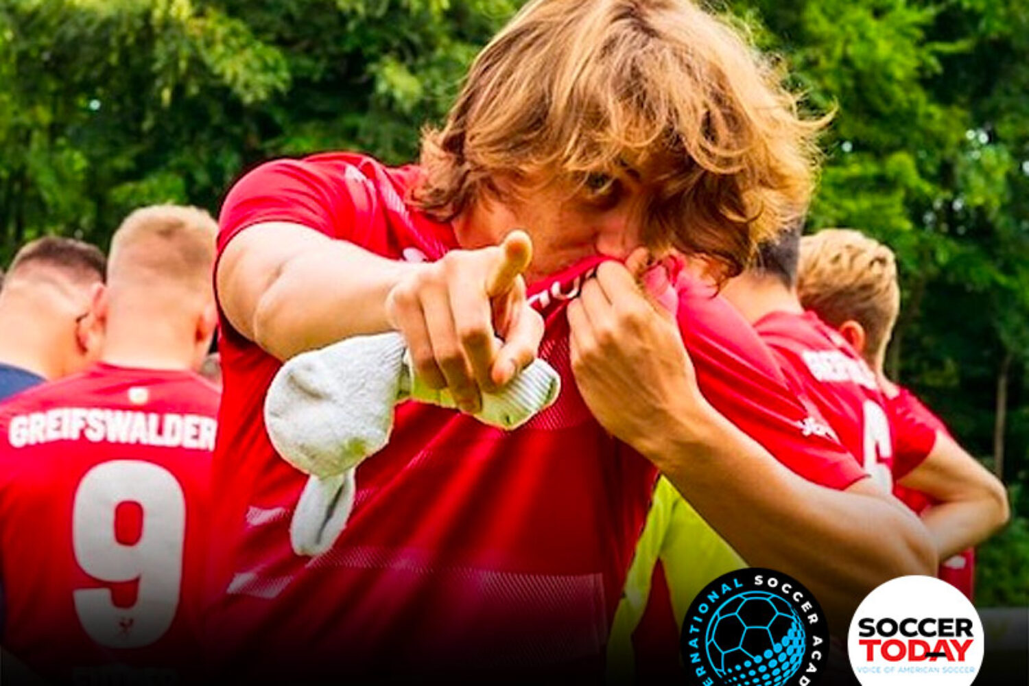 Soccer players in red jerseys celebrating on the field.