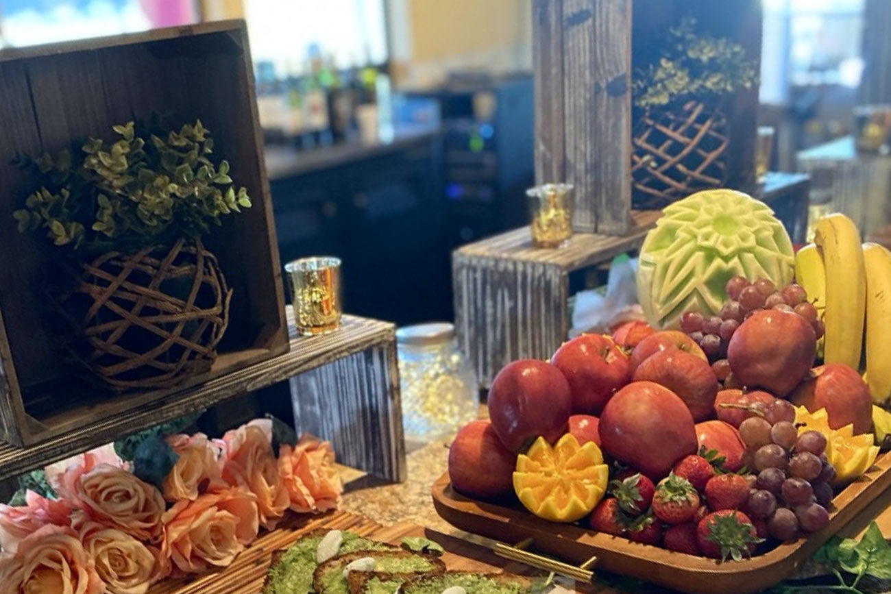 A beautifully arranged fruit and flower display with carved melon and assorted fruits.