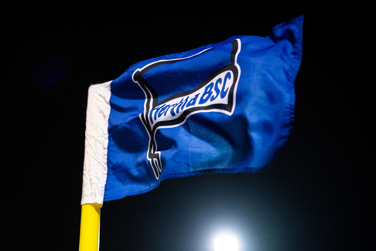 Blue Hertha BSC corner flag waving against a dark sky.