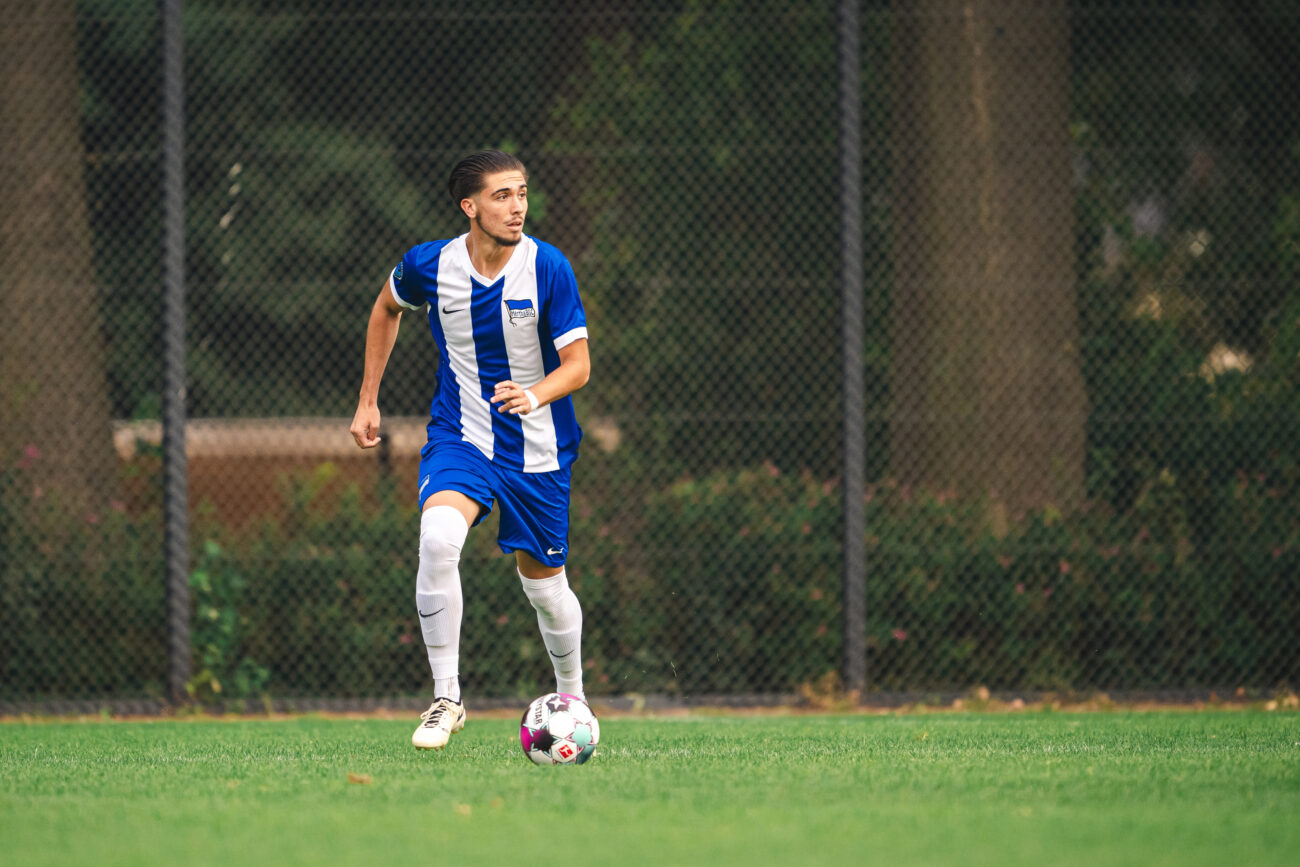 Soccer player in blue and white uniform controlling the ball on the field.