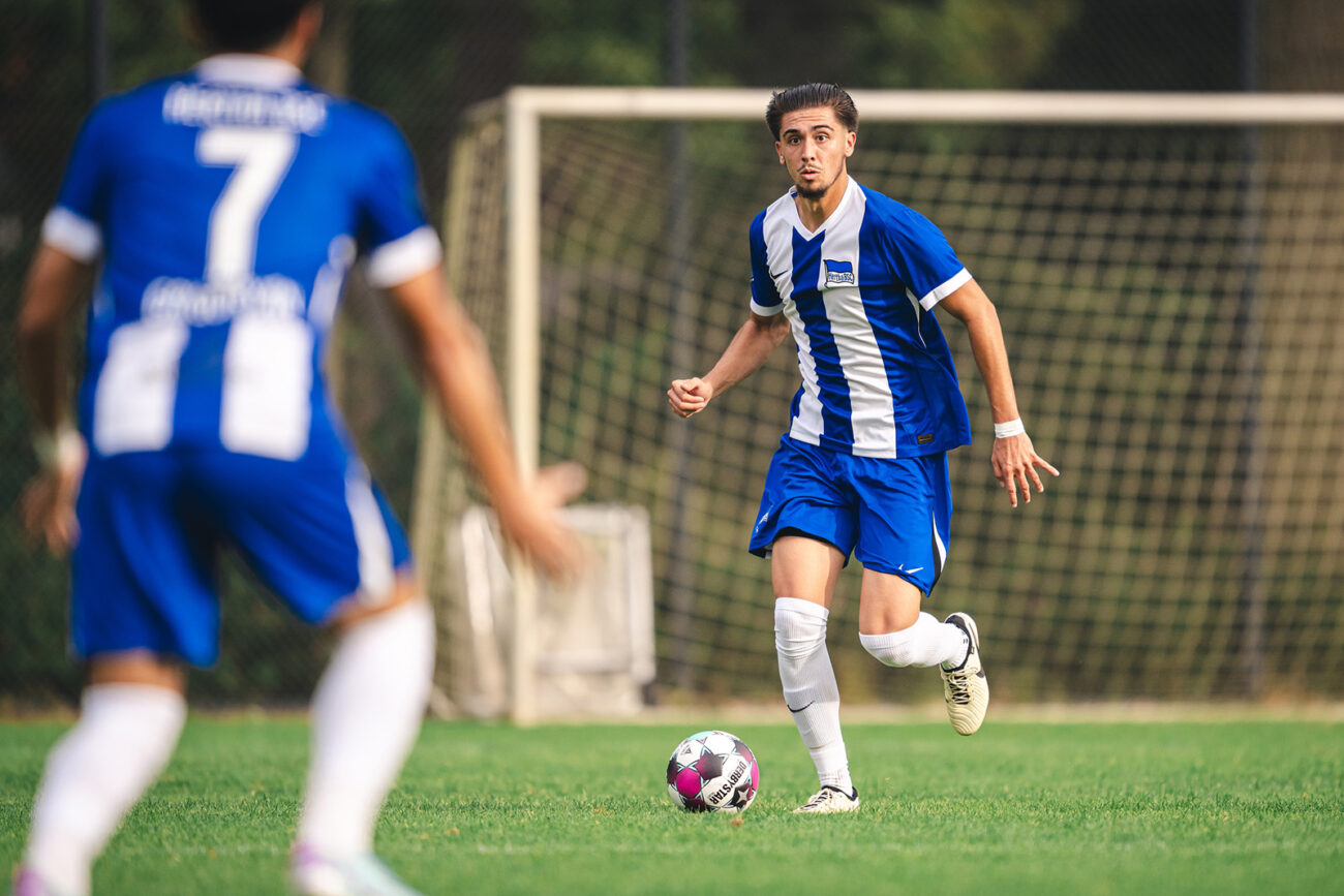 Two soccer players in blue and white uniforms on a field during a game.
