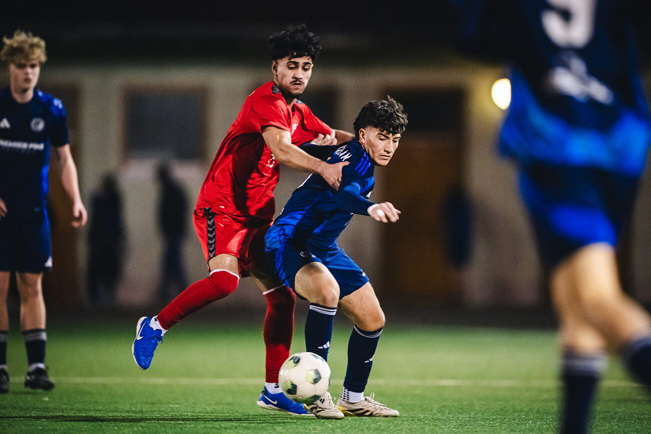 Two soccer players contesting for the ball during a night game.