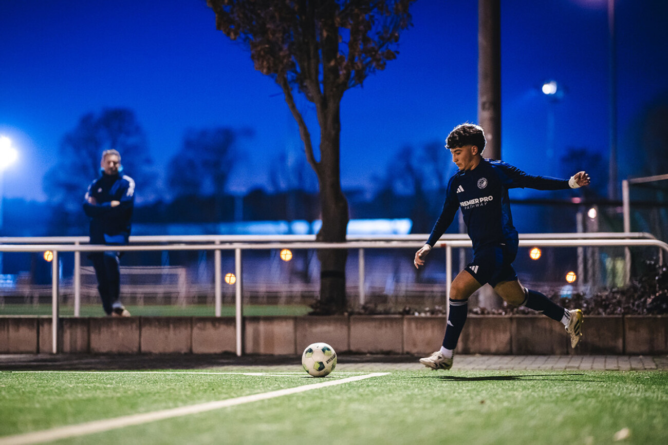 A soccer player prepares to kick the ball during a nighttime practice session.