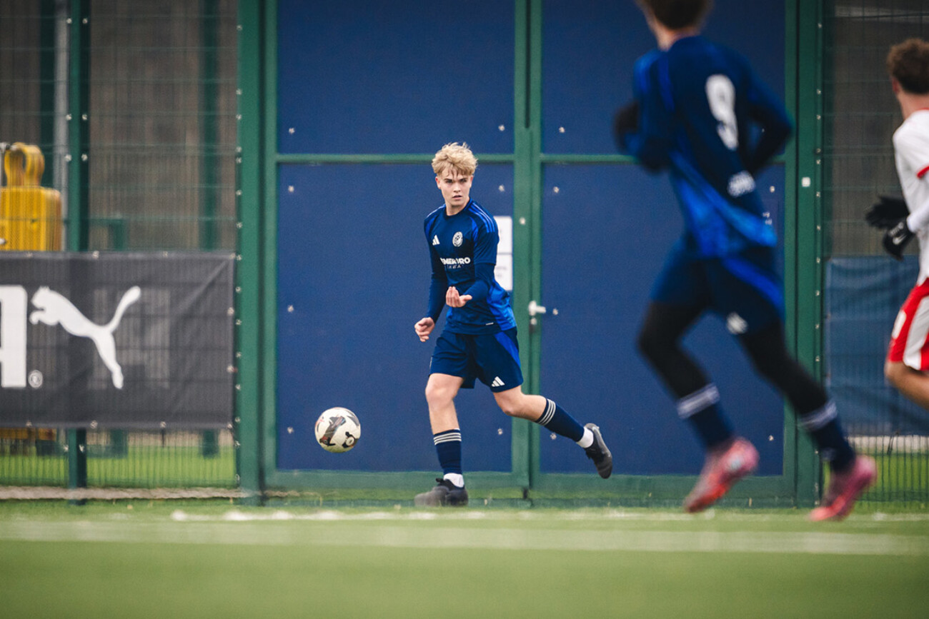 Young soccer player in blue jersey controlling the ball on the field.