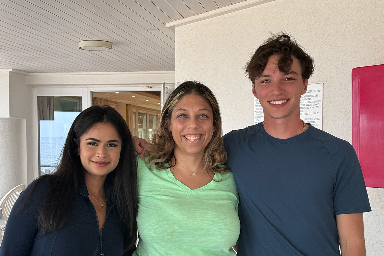 Three people smiling together indoors, showing friendship and happiness.